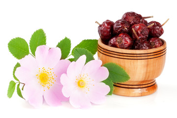Rosehip flowers with leaf and rosehip berries in a wooden bowl isolated on white background