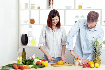 happy couple in love in kitchen making healthy juice from fresh orange