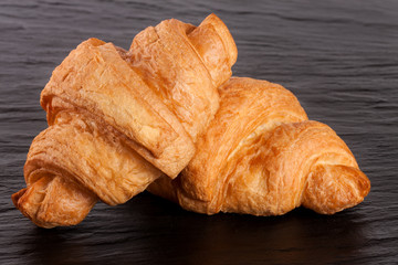 two croissant on black stone background closeup