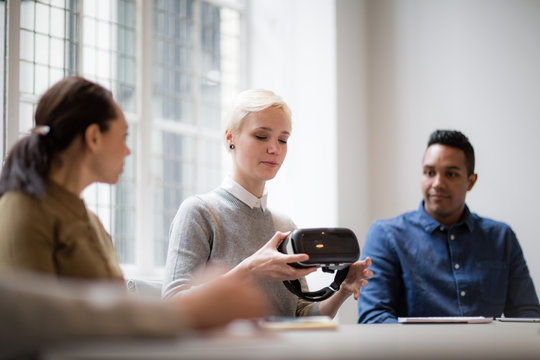 Designer presenting virtual reality headset in a meeting