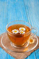 Herbal tea with fresh chamomile flowers on blue wooden background with copy space for your text