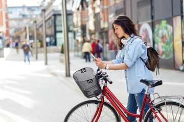 Beautiful young woman with bicycle in urban environment.