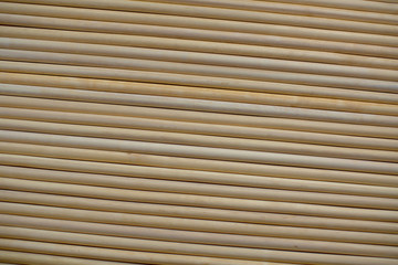A pattern of many parallel wooden round sticks, closely pressed together to one another