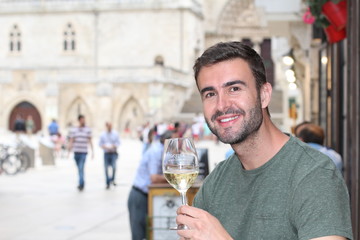 Striking man drinking white wine outdoors 