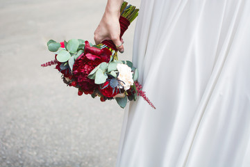 The bride is standing and holding a wedding bouquet