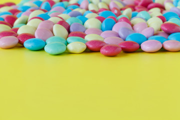 Colorful candies on yellow background