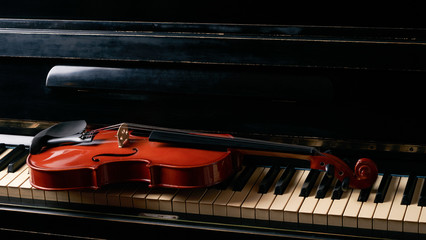 Classical musical stringed instrument violin on piano keys.  Fiddle on piano keyboard.