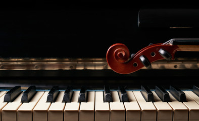 Classical musical stringed instrument violin on piano keys.  Fiddle on piano keyboard.