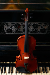 Classical musical stringed instrument violin on piano keys.  Fiddle on piano keyboard.