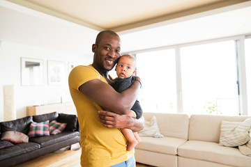 Young afro-american father holding his baby son in the arms