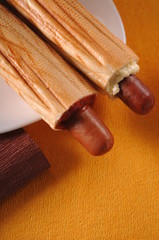 Two hot dogs on a yellow background