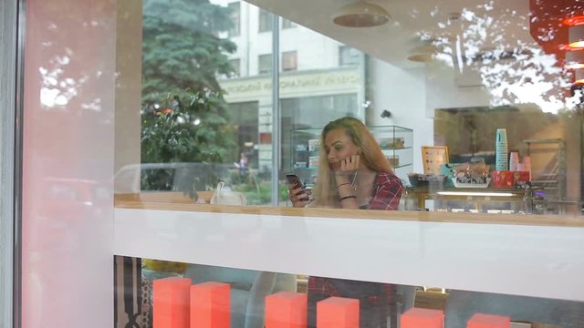 Girl listening to music in modern cafe . Street traffic is on window reflection