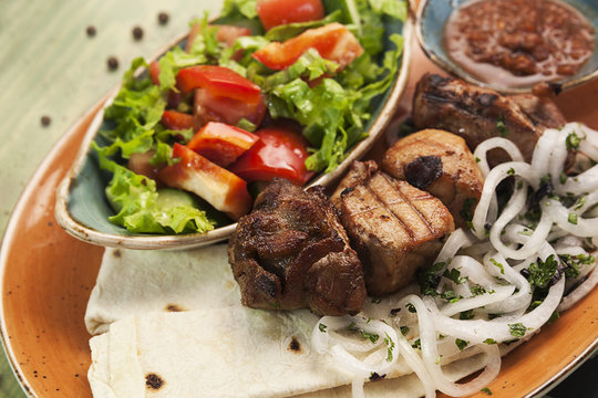 Shish kebab and vegetables on a plate, slices of a grilled grill