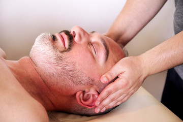 Man having treatment for his face at massage table, medicine concept. Masseur massaging mans face. Handsome man relaxing receiving facial massage at spa center relaxation therapy resort recreation.