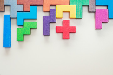 Obraz premium Different colorful shapes wooden blocks on beige background, flat lay. Geometric shapes in different colors, top view. Concept of creative, logical thinking or problem solving. Copy space.