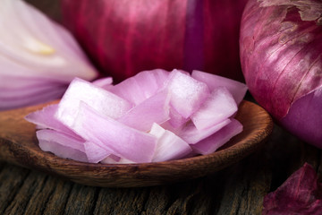 Close up of the sliced red onion and whole bulb onion on a wooden background