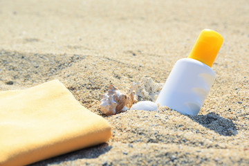 Sunscreen tube on the sand next to the beach. Empty copy space for Editor's text.