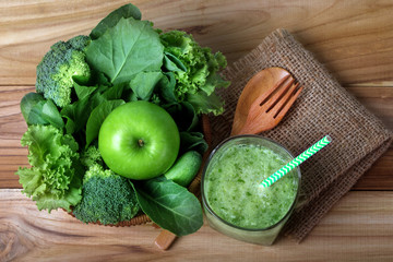 close up green apple with mixed green vegetable and green juice in a basket and wooden fork and spoon for healthy organic green food concept
