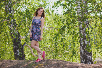Naklejka na ściany i meble Beautiful girl in a multi-colored dress with long hair in the forest in summer