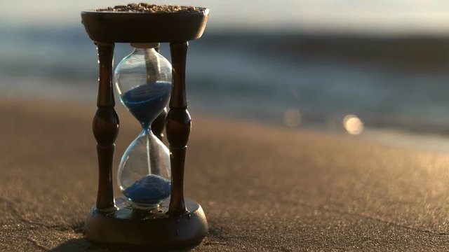 Hourglass on the beach sand beach. Daylight saving time concept