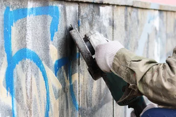 Poster Removal of graffiti on a concrete wall of an underground passage with the help of a angle grinder. © wolfness72