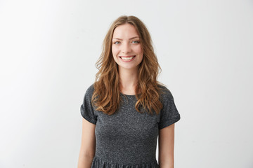 Portrait of young pretty cheerful girl smiling looking at camera over white background.