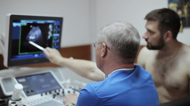 Doctor showing results of ultrasound diagnostic on the screen of sonogram device