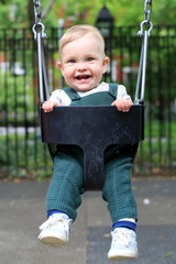 Little boy in overalls on the swing in the Park