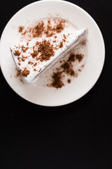 white layer cake chocolate in white dish on black background