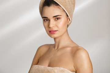 Close-up Portrait of a beautiful posh young woman after bath standing covered in towel.