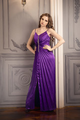 the girl in purple evening dress on background of vintage wall