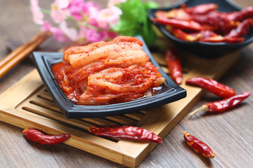 Korean kimchi in black plate on bamboo