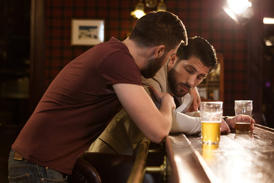 Young man talking to his drunk friend
