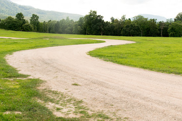 Dirt road curve on green grass park
