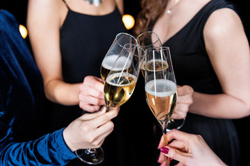 partial view of women holding glasses with champagne in hands