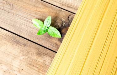 background with Bunch of spaghetti on wooden table with basil