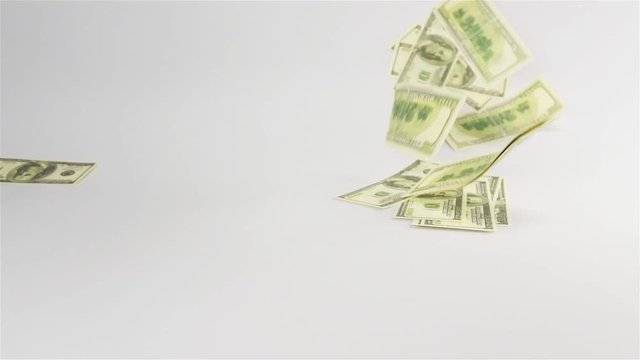 Slow motion. Few Dollars banknotes rain falling on white table cyclorama. 100 nominal
