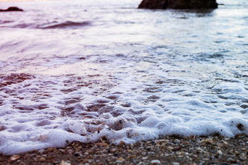 Sea foam rolling in over a rocky beach in Lagos, Portugal