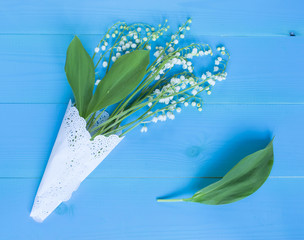 Bouquet of lilies of the valley on the blue wooden background.