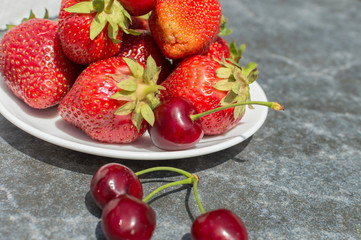 red strawberries and cherries on plate