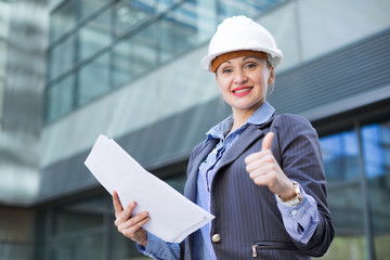Employee woman in helmet with paper documents