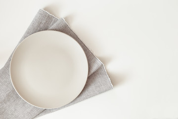 Empty plate with a napkin on white table