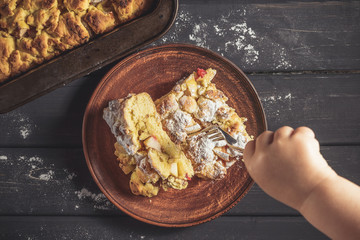 Kid is trying to pick up a piece of pie