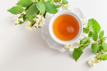 Cup of tea with jasmine flowers on a white table