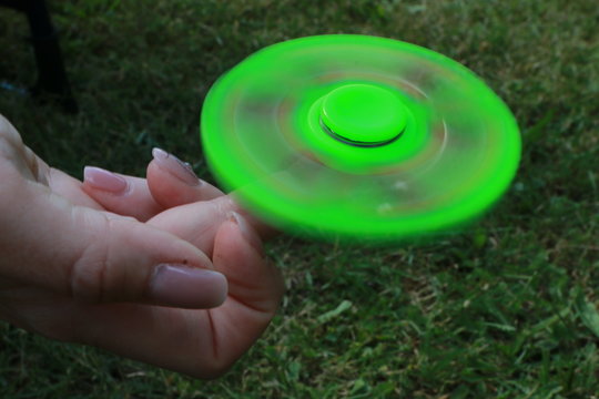 Fidget Spinner in neon gr&uuml;n rotiert sehr schnell auf einem Finger