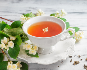Cup of tea with jasmine flowers on a white table