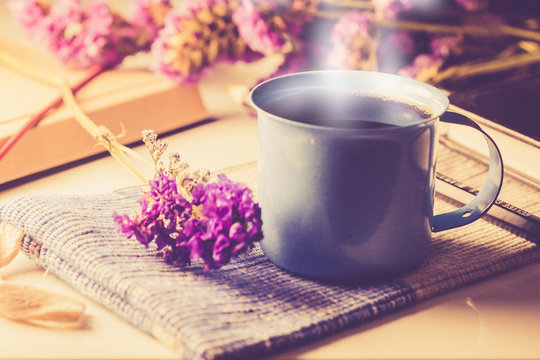 Violet dried flowers and  blue cup coffee on wooden table with vintage image style and soft light