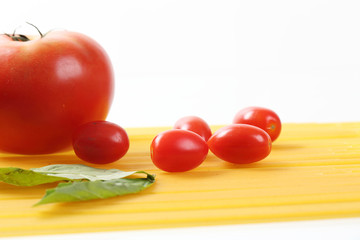 Raw spaghetti noodle with tomatoes and basil isolated in white background