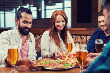 friends eating pizza with beer at restaurant