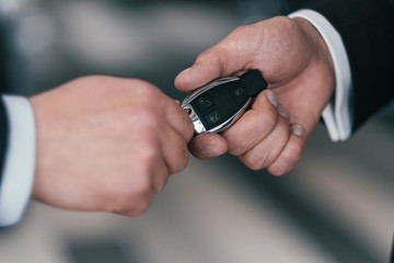 Giving a key from new car at dealership showroom